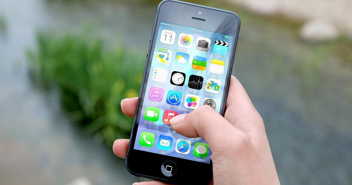 ems查询 App 在手机屏幕上的首页界面实拍效果，浅米色背景中手机竖立展示单号输入框与核对结果卡片，桌面散落一支笔和便签纸，光线柔和自然